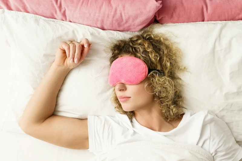 woman in bed with sleepmask dreaming of a white snake