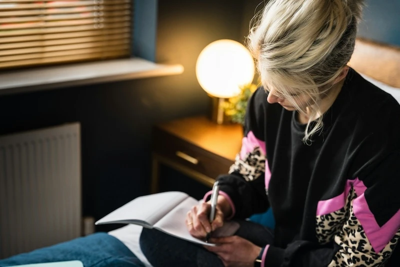 woman writing in dream journal in bed