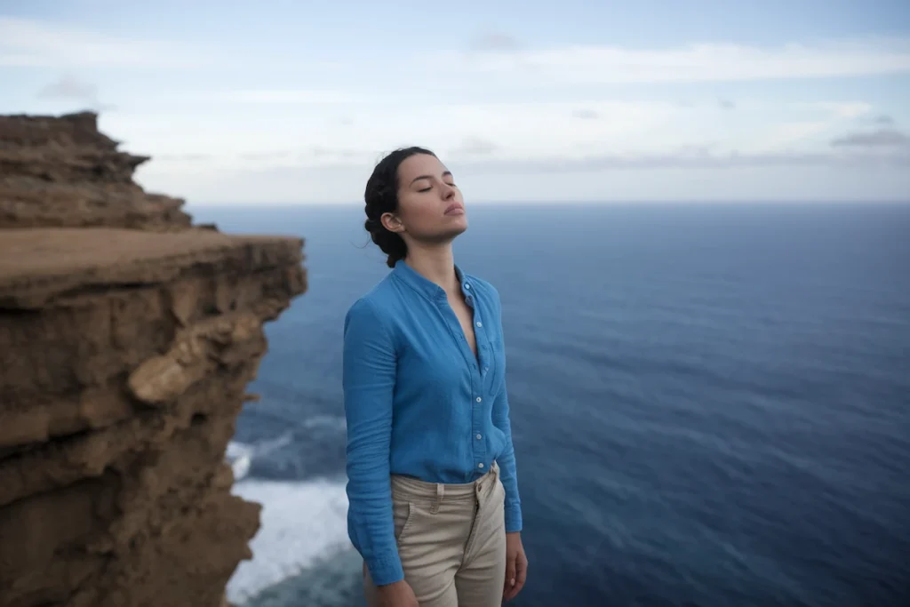 woman standing on the edge of a cliff looking relaxed with her eyes closed. She feels no fear in her dream